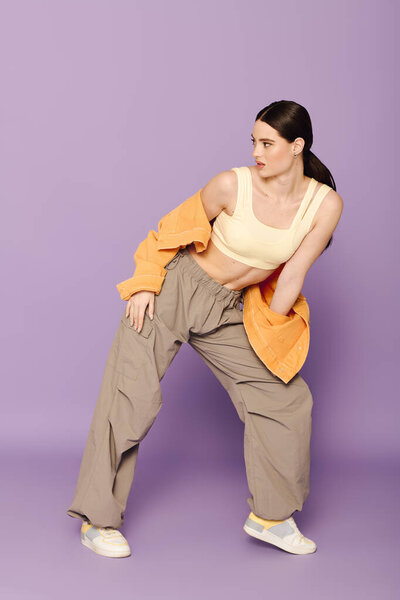 Молодая и модная женщина занимает уверенную позу в повседневной, но стильной одежде.