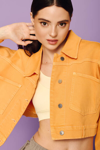 Уверенная женщина демонстрирует свое модное чувство стиля на пастельном фоне, излучающем стиль.