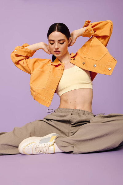 Молодая женщина обнимает свою стильную сторону, одновременно занимая динамичную позу в красочной обстановке..