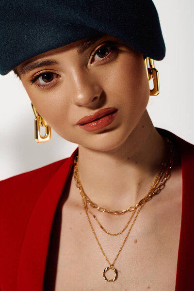 Уверенная женщина позирует в современной одежде и ярких ювелирных изделий при мягком освещении.