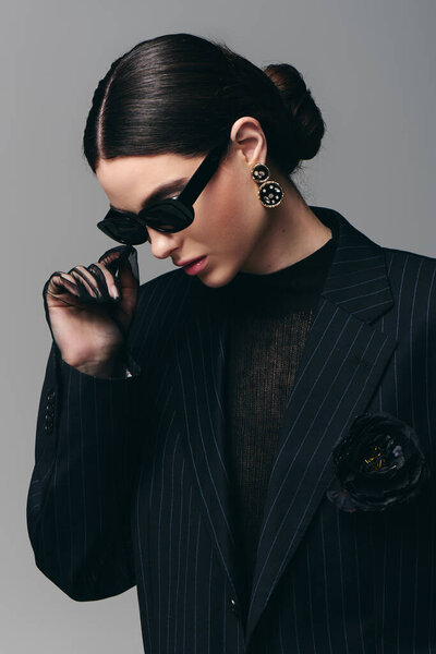 A stylish young woman in a tailored black suit exudes confidence and elegance.