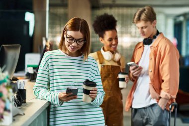 Üç meslektaş, bir otel lobisinde akıllı telefonları ile uğraşırken kahvenin tadını çıkarıyor..