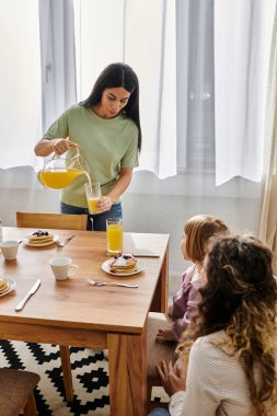 İki kadın kızlarıyla keyifli bir kahvaltı anı paylaşıyor, güzel anılar yaratıyorlar..