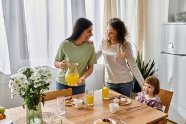 İki kadın birbirlerini severken kızları kahvaltı masasında gülümserken ve kreplerin tadını çıkarırken..