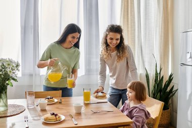 İki kadın genç kızlarına kahvaltı hazırlıyor. Parlak, hoş bir dairede..