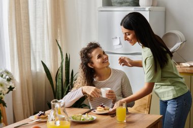 İki neşeli lezbiyen kadın, parlak dairelerinde keyifli bir brunch 'ın tadını çıkarıyorlar..