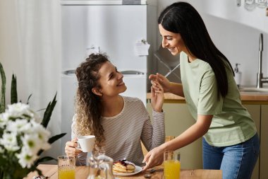 İki neşeli lezbiyen kadın, aşkla dolu modern dairelerinde kahvaltıdan zevk alıyorlar..