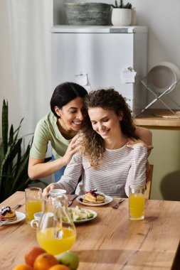 Mutlu lezbiyen çift, sıcak ve şık evlerinde keyifli bir kahvaltıyı paylaşıyor..