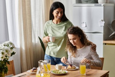Neşeli lezbiyen çift şık evlerinde keyifli bir kahvaltı yapıyor, mutluluğu kucaklıyorlar..