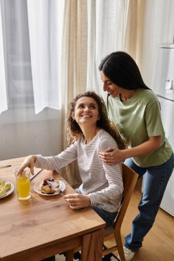 Two happy women share a loving moment over breakfast in their stylish home atmosphere.