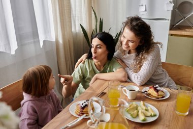 İki sevgi dolu anne, sıcak bir kahvaltı masasında kızlarıyla eğlenceli anlar paylaşır..