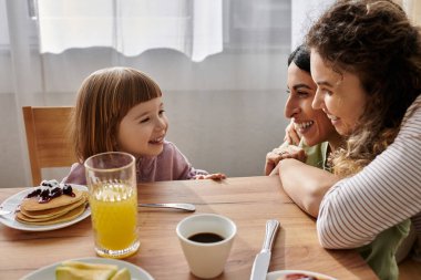 İki kadın ailelerini ve ilişkilerini kutlamak için kızlarıyla sıcak bir kahvaltı yapıyorlar..