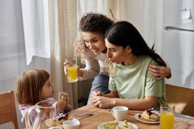 İki sevgi dolu anne, şık bir dairede genç kızlarıyla keyifli bir kahvaltı yapıyorlar..