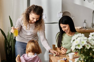 İki kadın şık bir dairede genç kızlarıyla keyifli bir kahvaltı yapıyorlar..