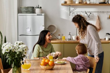 İki kadın modern bir dairede kızlarıyla zevkle yemek yiyorlar..