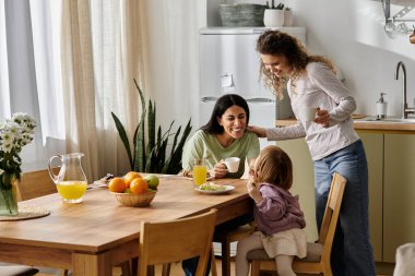 İki anne, kızlarıyla birlikte güzel bir mutfak atmosferinde kahvaltıdan zevk alır..