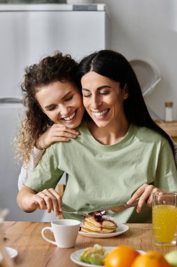 Mutlu lezbiyen çift, keyifli bir kahvaltıyı paylaşıyor. Lezzetli gözlemelerin ve birlikteliğin tadını çıkarıyorlar..