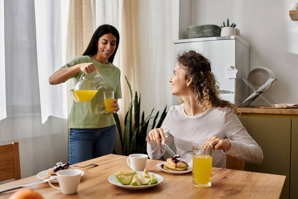 Две весёлые лесбиянки наслаждаются восхитительным завтраком в своей стильной квартире, разделяя улыбки и любовь.