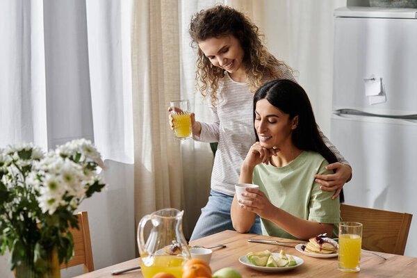 Две счастливые лесбиянки разделяют теплый момент за завтраком, наслаждаясь компанией друг друга дома.