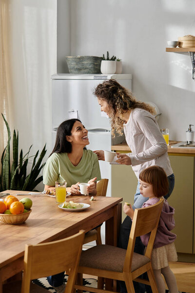 В уютной квартире две женщины весело общаются, пока их дочь наслаждается завтраком..