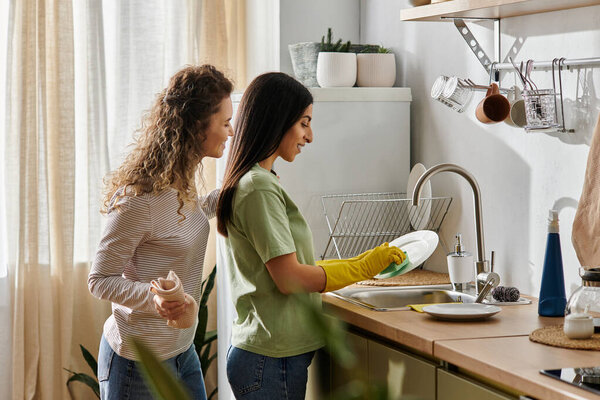 happy lesbian couple engage in daily chores together while enjoying their cozy apartment space.