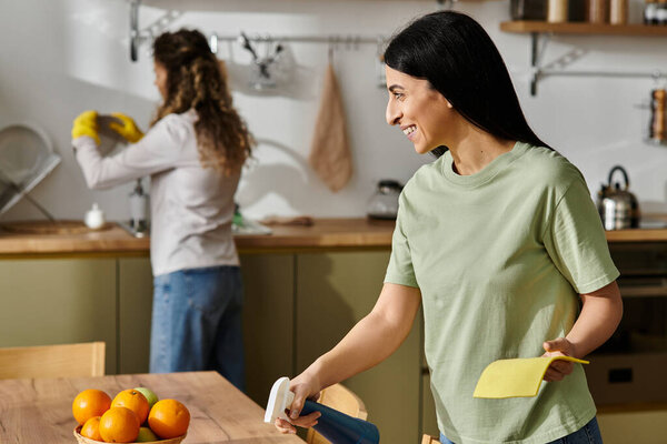 Two happy women share a warm moment while cleaning and enjoying each other's company at home.