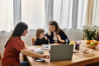 Sıcak bir dairede, iki kadın yemek masasında kızlarıyla vakit geçirir..