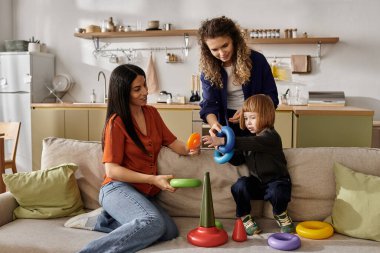 İki ilgili anne kızlarının renkli oyuncaklarla oynamasına seviniyor..