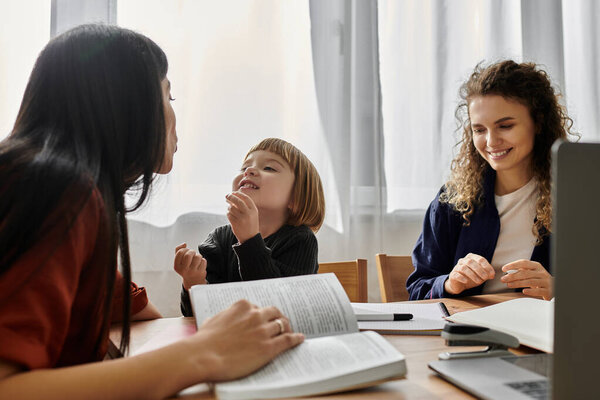Две женщины делят радостные моменты со своей дочерью дома в окружении книг и тепла.