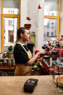 Genç bir kadın hayat dolu bir kafede kahve servisi yaparken espresso makinesini ustaca kullanıyor..