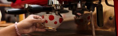 A young woman enjoys her time in a vibrant cafe while preparing her coffee. clipart