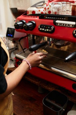 Genç bir kadın hayat dolu bir kafede espresso makinesini hevesle çalıştırıyor, içecekler hazırlıyor..