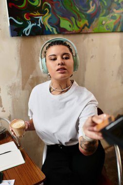 Genç bir kadın, canlı bir kafe atmosferine dalmış müzik dinlerken içkisinin tadını çıkarıyor..