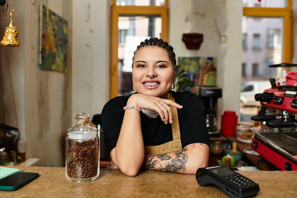 В оживленном кафе молодая женщина сияет, положив подбородок на руку, излучая тепло..