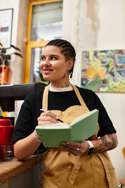 Молодая женщина стоит в оживленном кафе, улыбаясь, когда она пишет в блокноте, излучая тепло.