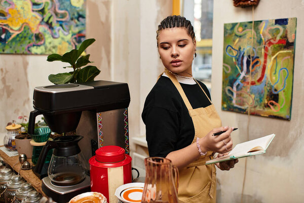 Молодая женщина со стильным взглядом стоит у кафе, записывая в блокнот, погруженная в творчество.