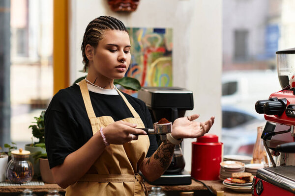 Молодая женщина сосредоточена на приготовлении кофе, демонстрируя свои навыки в местном кафе.