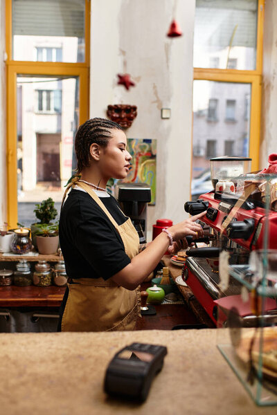 Молодая женщина умело управляет кофеваркой во время подачи кофе в ярком кафе.