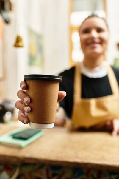 Happy woman offers a cup of coffee while engaging with customers in a charming cafe.