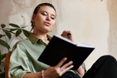 Genç ve güzel bir kadın bir kafede rahatlar, bir kitap okumakla ilgilenir..