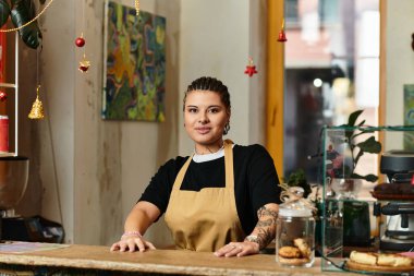 Genç bir kadın, kafeterya tezgahında kendine güveni tam bir şekilde duruyor. Parlak gülümsemesiyle müşterileri kendine çekiyor..