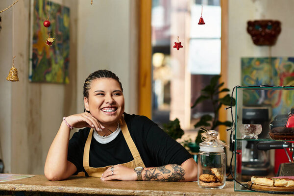 Brightly smiling, a young woman relaxes behind the cafe counter surrounded by delightful pastries.