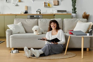 Yumuşak bir halıya oturan genç bir kadın, köpeği yakınlarda dinlenirken günlüğünü yazıyor..