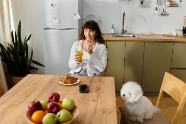 Meyve ve kruvasanla lezzetli bir brunch 'ın tadını çıkaran genç bir kadın..