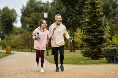 Joyful couple enjoys a lively stroll in the park, sharing laughter and love amidst natures beauty. clipart