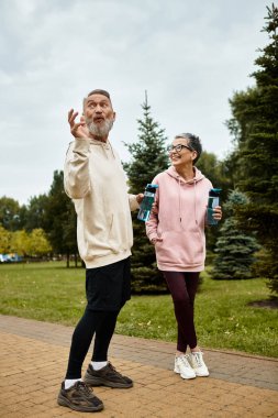 Sevgi dolu bir çift huzur parkında gezer, gülümsemelerini paylaşır ve neşeli sohbetlere dalarlar..