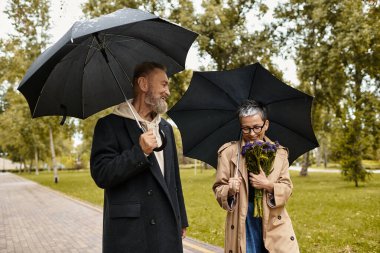 Sevgi dolu bir çift, doğa tarafından çevrelenmiş yağmurdan korunurken birbirlerine eşlik etmekten zevk alır..