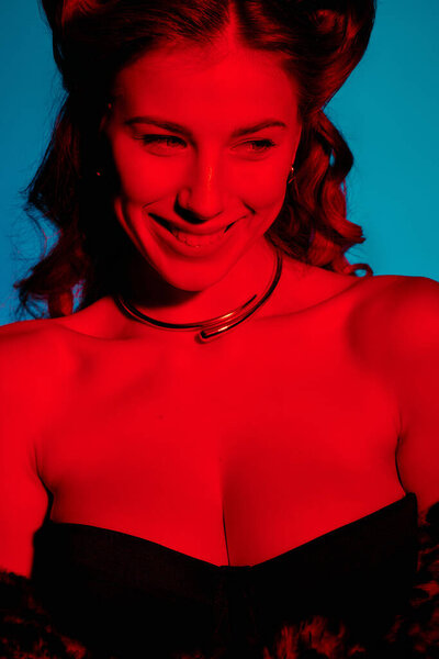 Stylish woman in chic attire smiles confidently against bold dusk colors.