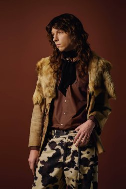 Yakışıklı genç adam belirgin desenleri ve dokuları olan ayırt edici bir kıyafetle gururla ayakta duruyor..