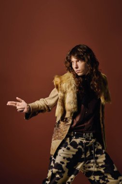 Şık giyinmiş genç bir adam sanatsal bir ortamda özgüvenle poz verir..